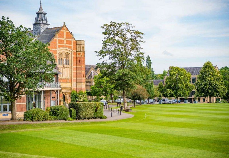 Red-brick college building with pitched roofs, chimneys and surrounding green lawns, Tonbridge.